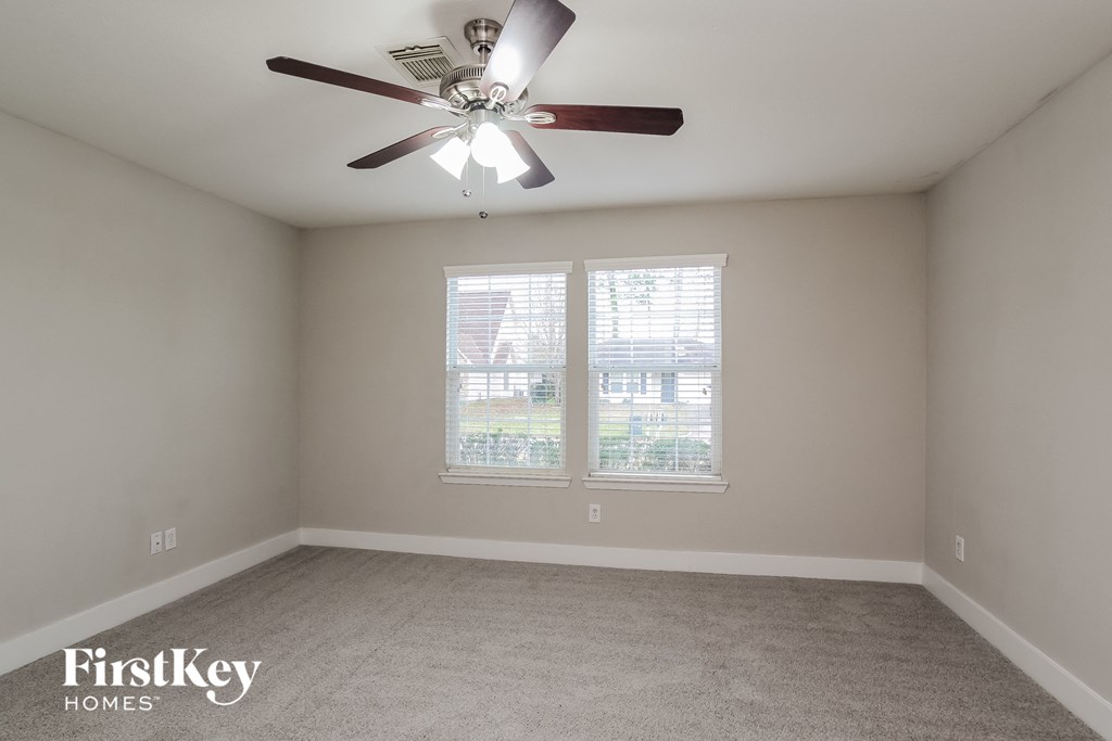 a bedroom with a ceiling fan and two windows