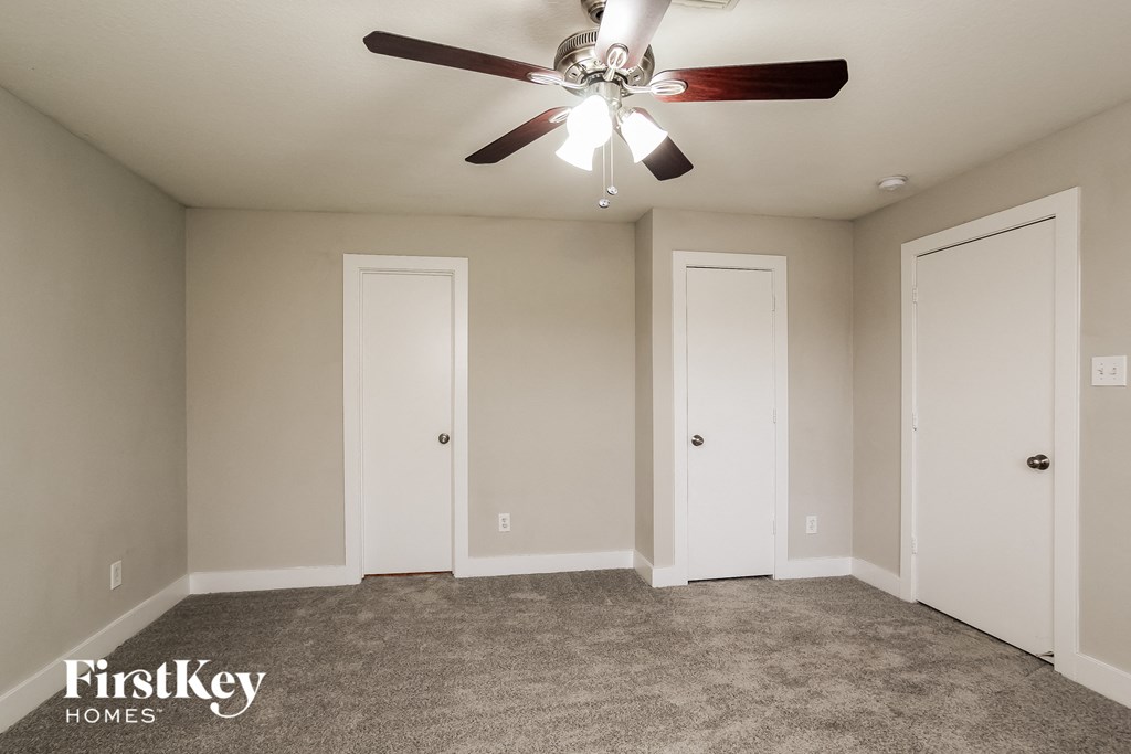 a living room with a ceiling fan and three doors