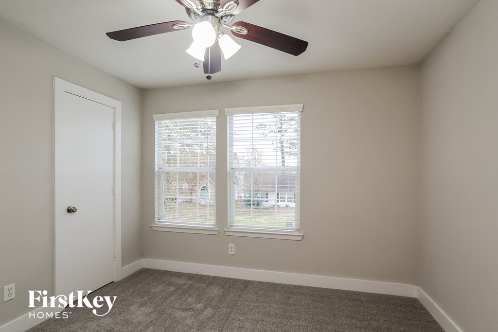 a bedroom with two windows and a ceiling fan