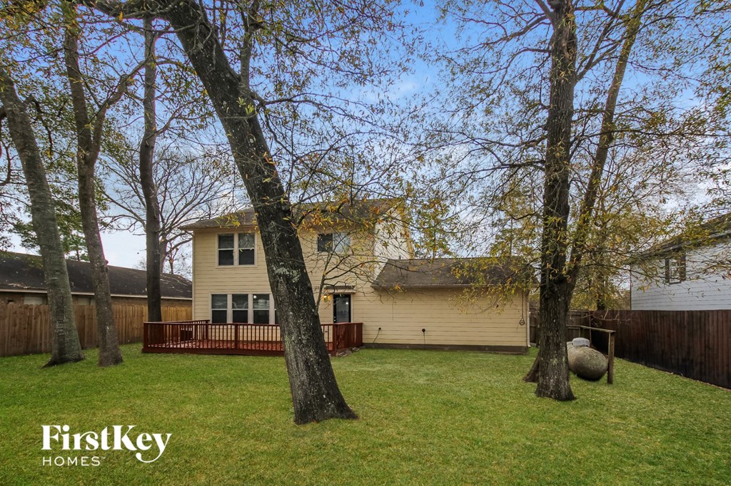 a backyard with trees and a yellow house