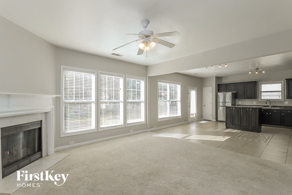 an empty living room with a fireplace and a ceiling fan