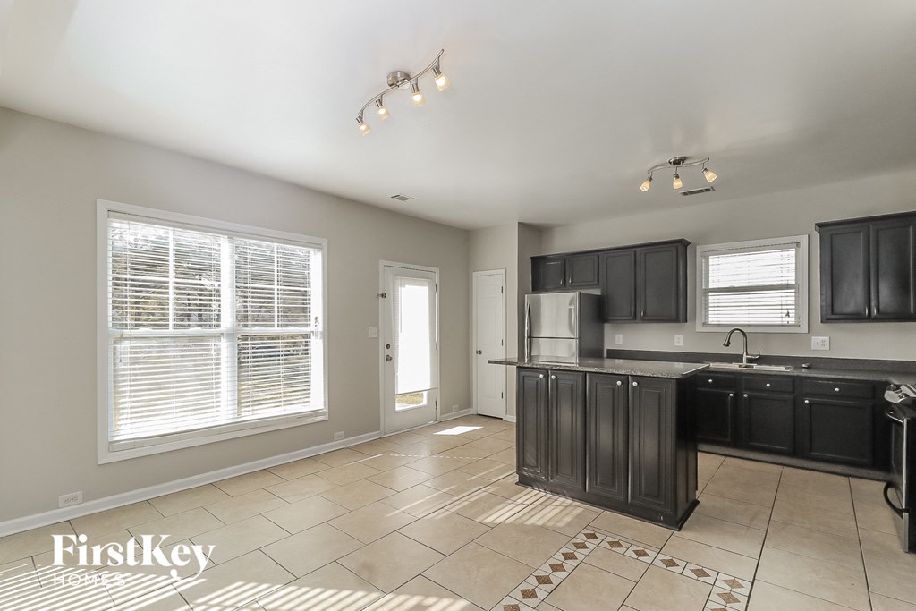 a kitchen with black cabinets and tile floors and a large window