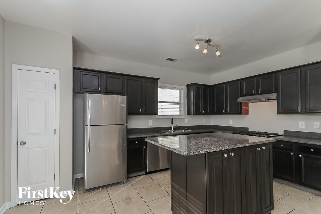 a kitchen with black cabinets and a stainless steel refrigerator