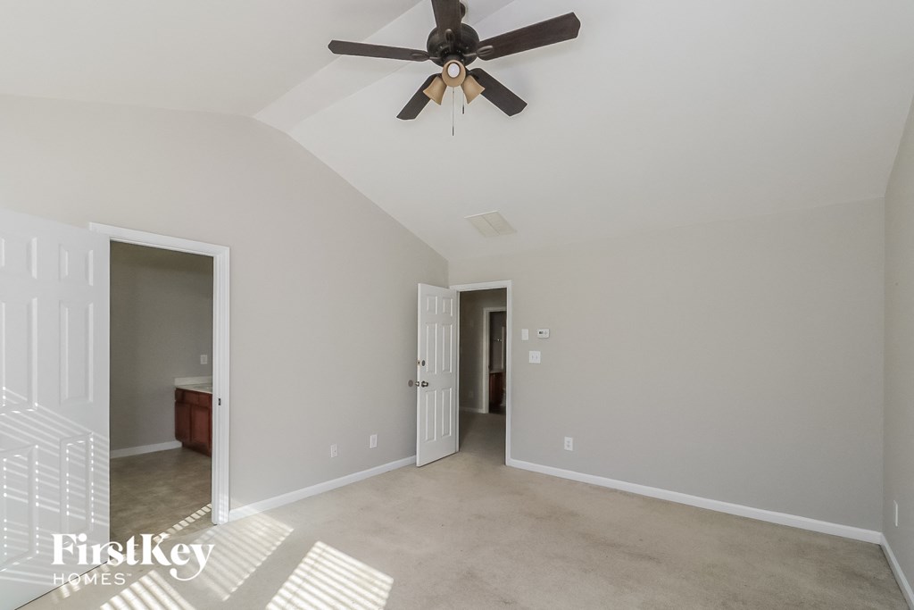 a living room with a ceiling fan and a door to a bathroom