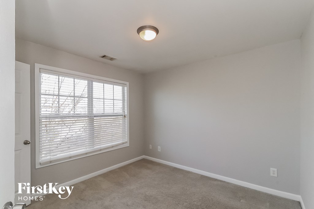 the living room of a home with a large window and white walls