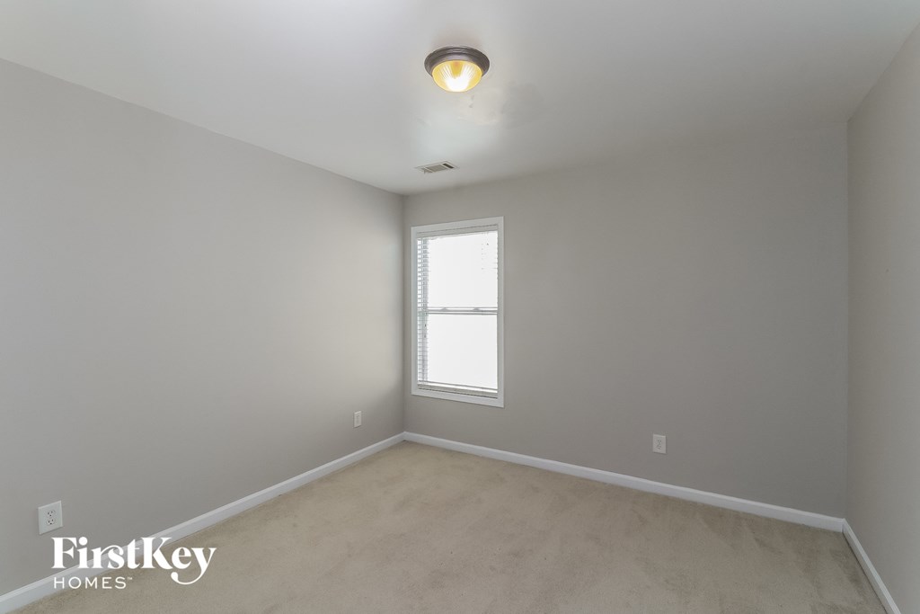 the living room of a home with white walls and a window