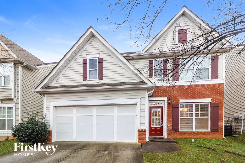 A house with a red door and a garage is for sale.
