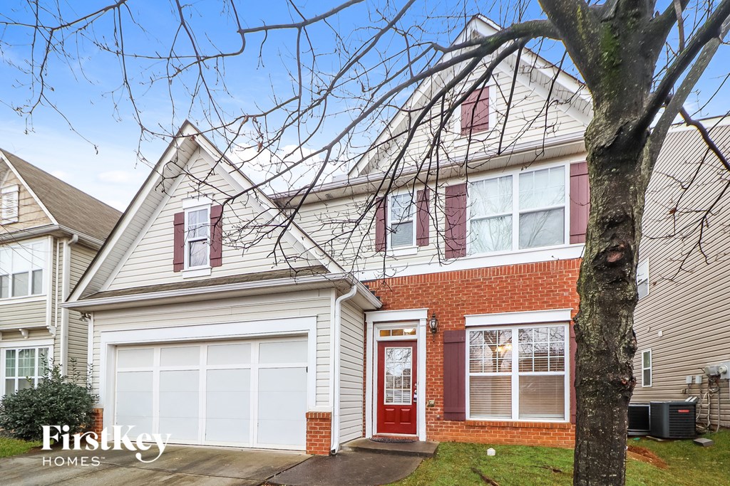 A house with a red door and a tree in front.