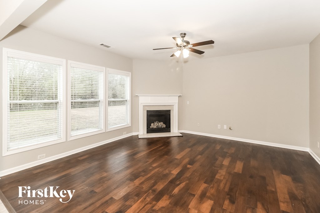 A spacious room with wooden floors and a fireplace.
