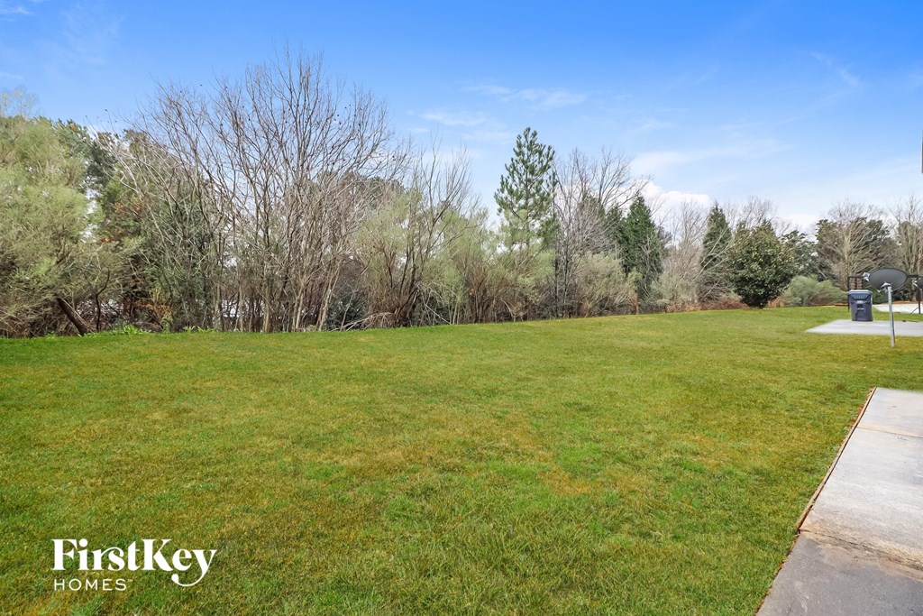 A grassy field with trees and a FirstKey Homes logo.