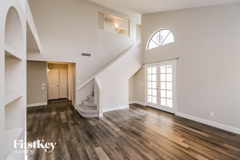an empty living room with hardwood floors and a staircase