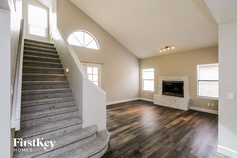 an open living room with a staircase and a fireplace