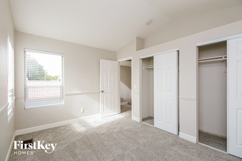 a bedroom with two closets and a window and a carpeted floor