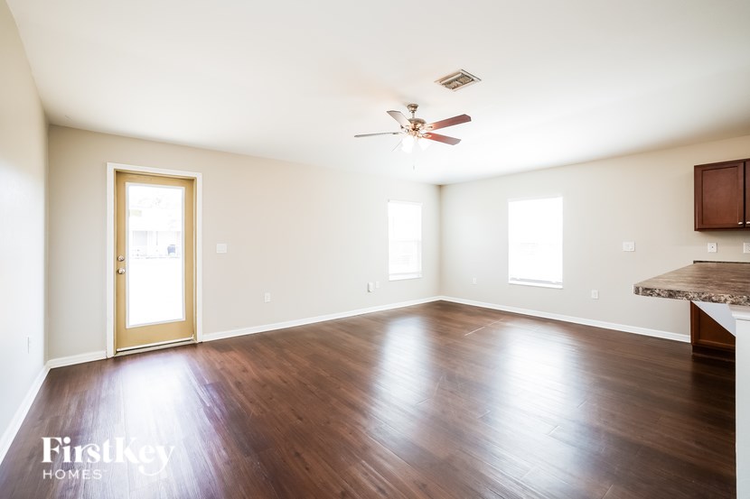 A spacious room with wooden floors and a ceiling fan.