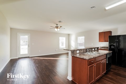 A kitchen with wooden floors and a black refrigerator.