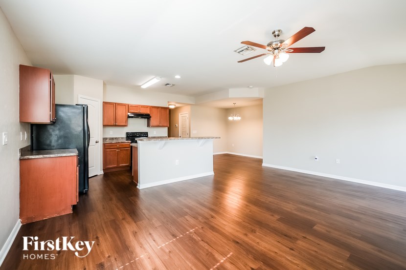 A spacious kitchen with wooden floors and a ceiling fan.