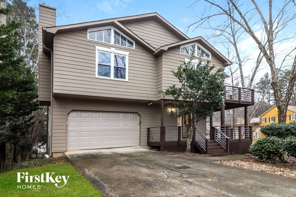 A house with a garage and a tree in front.