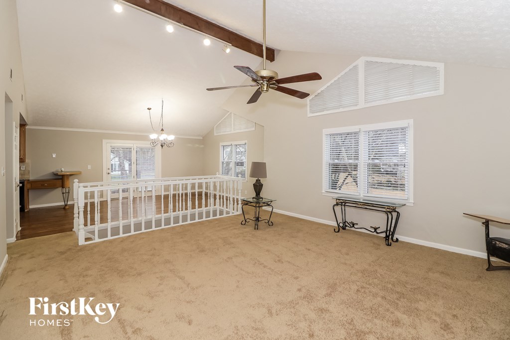 A spacious room with a fan, a table, and a baby crib.