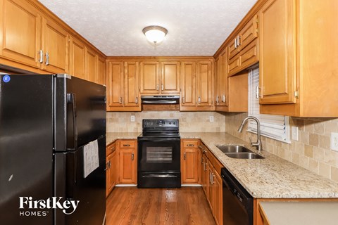 A kitchen with wooden cabinets and a black refrigerator.