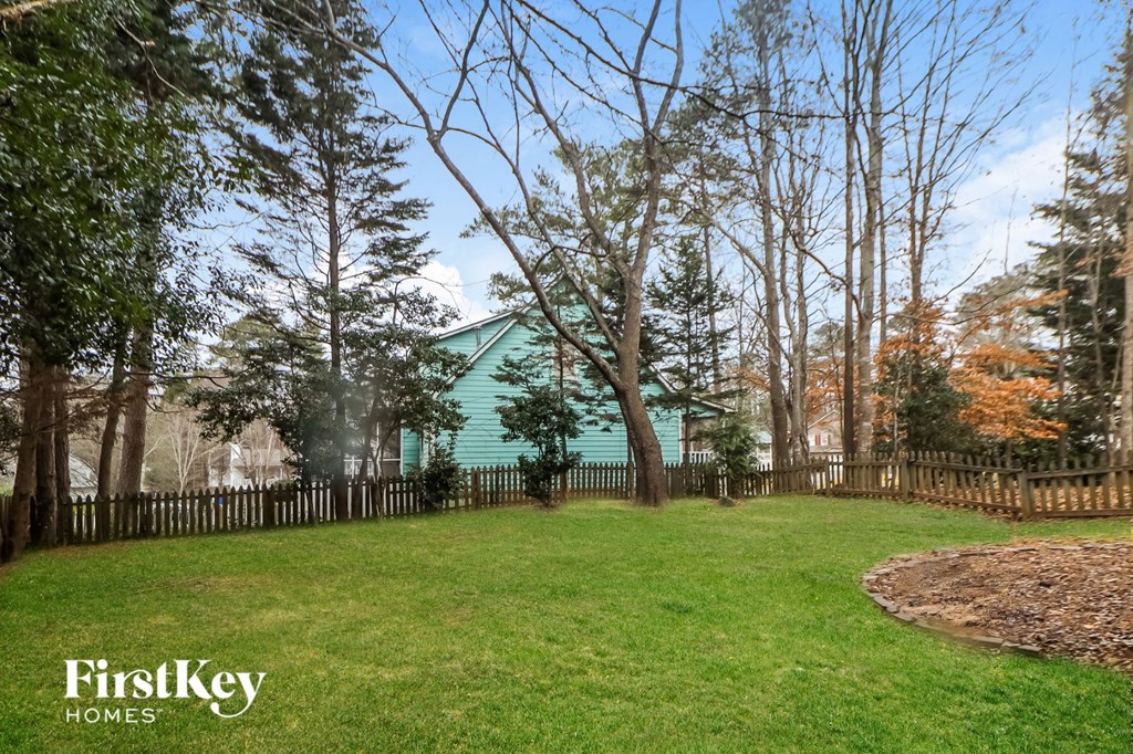 A FirstKey Homes sign is displayed in a yard with a fence and trees.