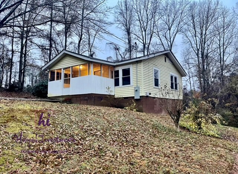 A house with a white and yellow exterior is surrounded by trees.