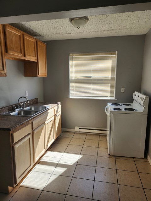 A kitchen with a white stove and brown cabinets.