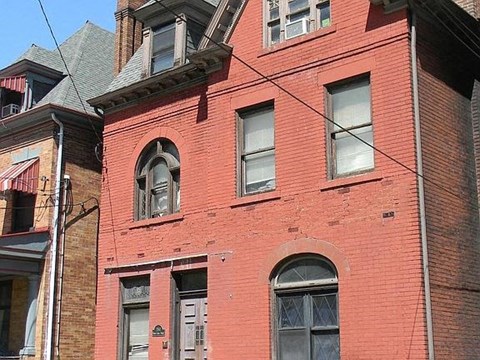 A red brick building with a grey door and windows.
