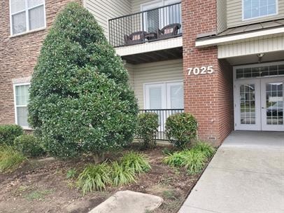 A green tree in front of a building with the number 7025 on it.