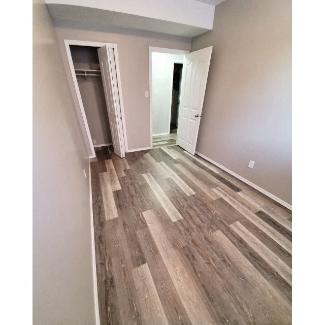 a room with wood flooring and a hallway with a closet