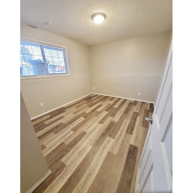 an empty bedroom with wood floors and a window