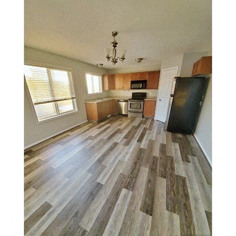 a kitchen with wood floors and a black refrigerator