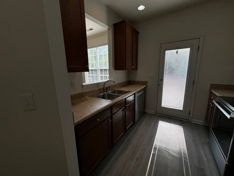 A kitchen with wooden cabinets and a window above the sink.