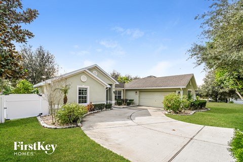 a beige house with a driveway and a white fence