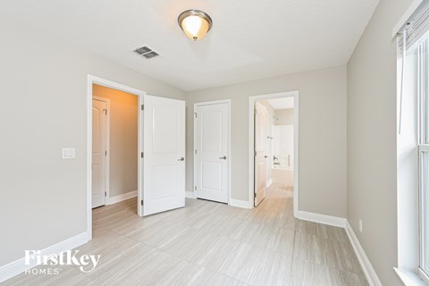 a renovated living room and hallway with white floors and white doors