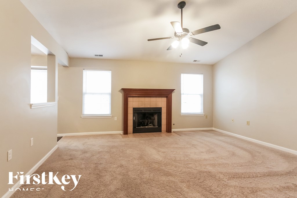 A spacious room with a fireplace and a ceiling fan.
