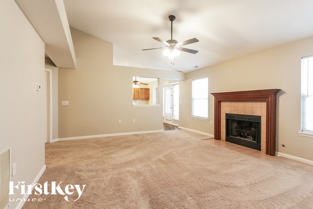 A spacious living room with a fireplace and a ceiling fan.