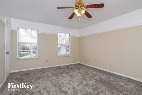 the living room of a home with carpet and a ceiling fan