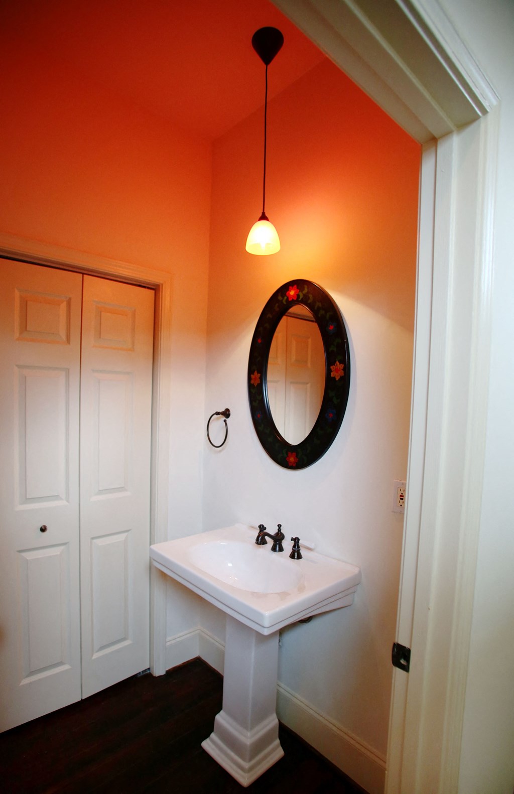 an orange bathroom with a white sink and a mirror