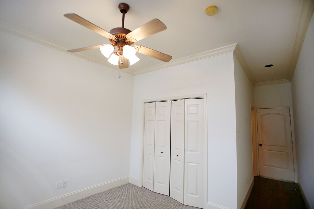 a bedroom with a ceiling fan and two closet doors
