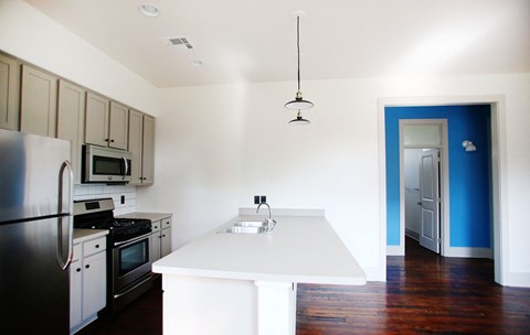 A kitchen with a white island and a black refrigerator.