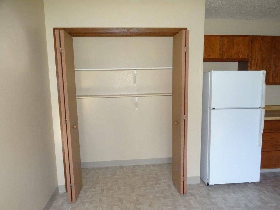 an empty kitchen with a white refrigerator and an open door