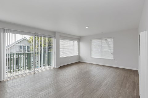 A room with a sliding glass door and wooden flooring.