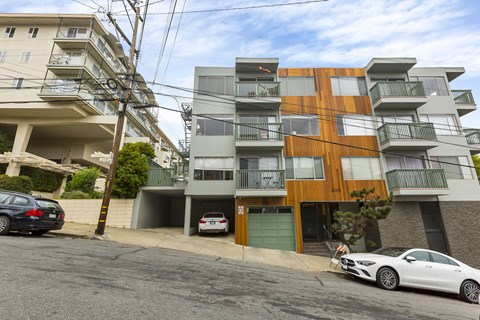 A modern apartment building with a white car parked in front.