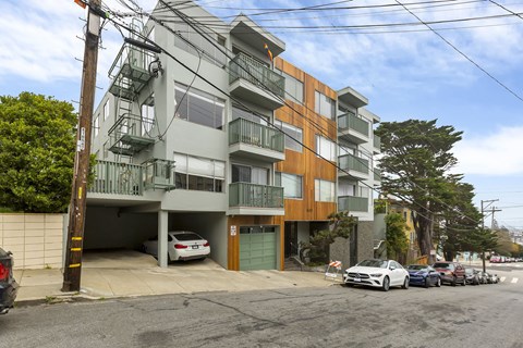 A white car is parked in the garage of a multi-story apartment building.