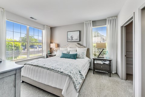a bedroom with a large bed and windows