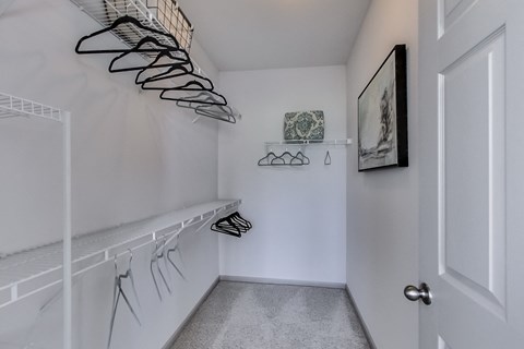 a room with a staircase and a closet with shoes on a shelf