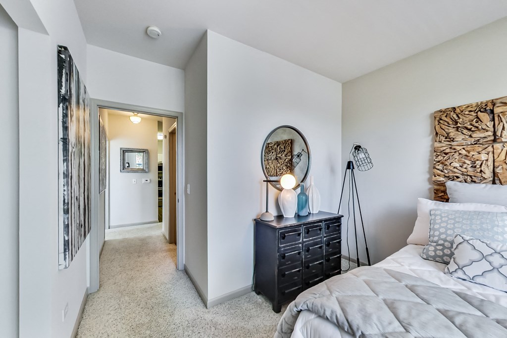 an open bedroom with a bed and a hallway to a bathroom