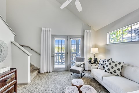 a living room with a couch and a chair and a door to a balcony