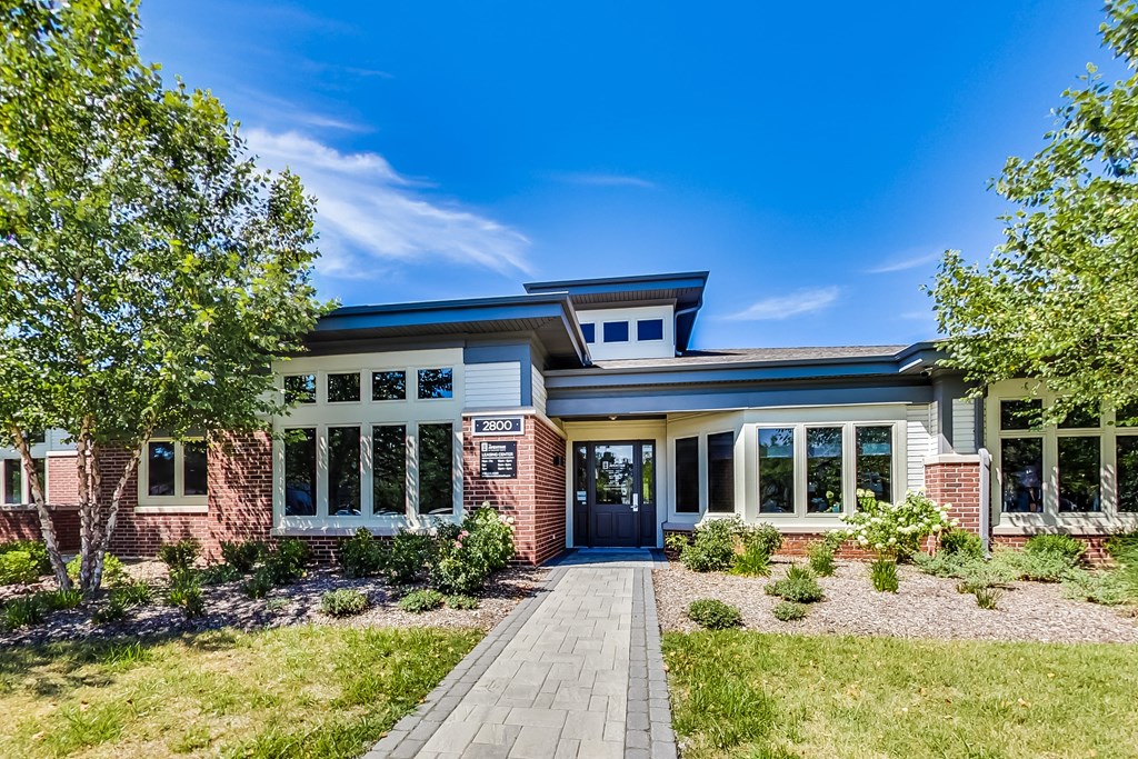 the front of a house with a walkway and trees