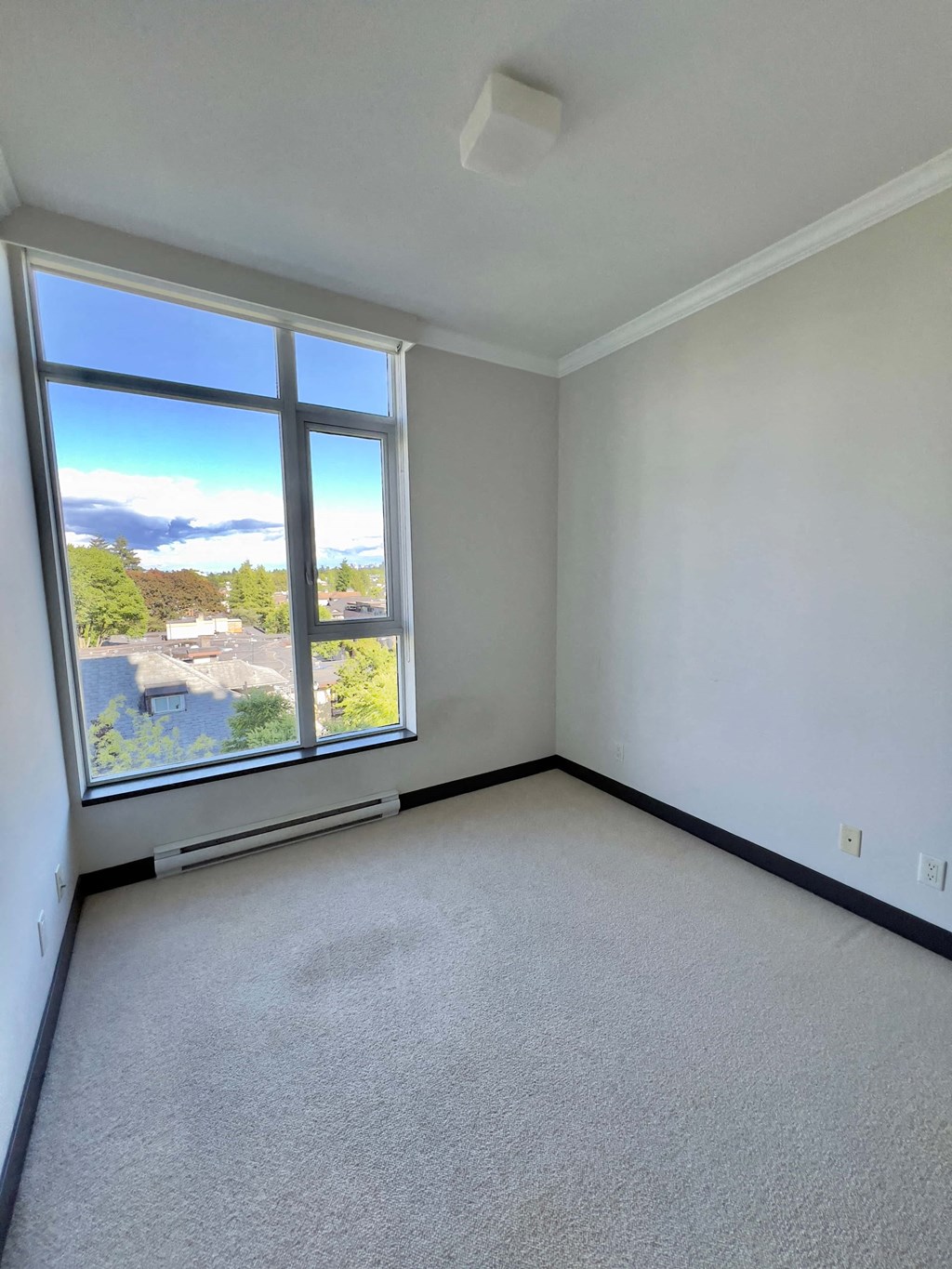 an empty living room with a large window and white walls
